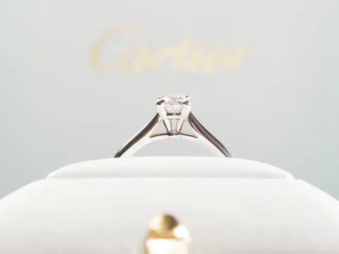 A Cartier solitaire engagement ring standing in its open red Cartier box