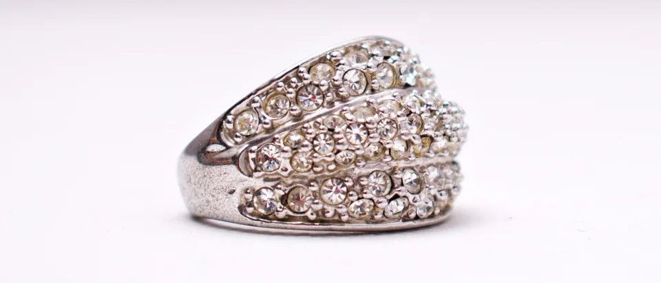 A wide dome ring set with rows of diamonds on a pale background