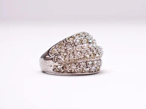 A wide dome ring set with rows of diamonds on a pale background