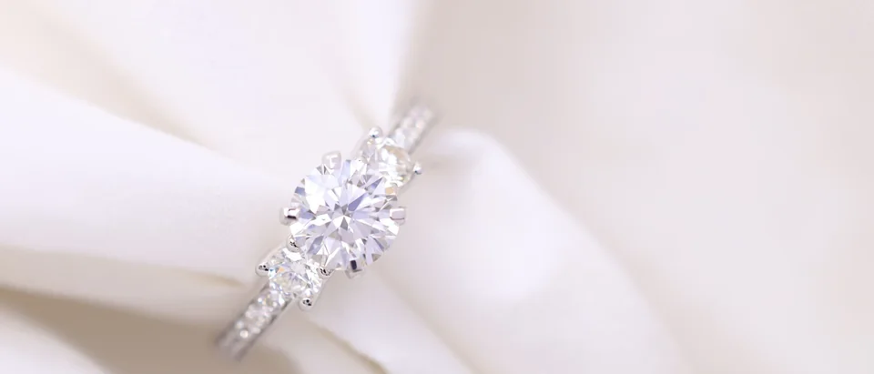 A diamond engagement ring with a round center stone held in folds of white silk