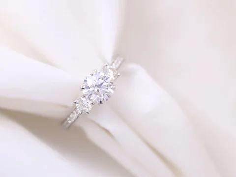 A diamond engagement ring with a round center stone held in folds of white silk