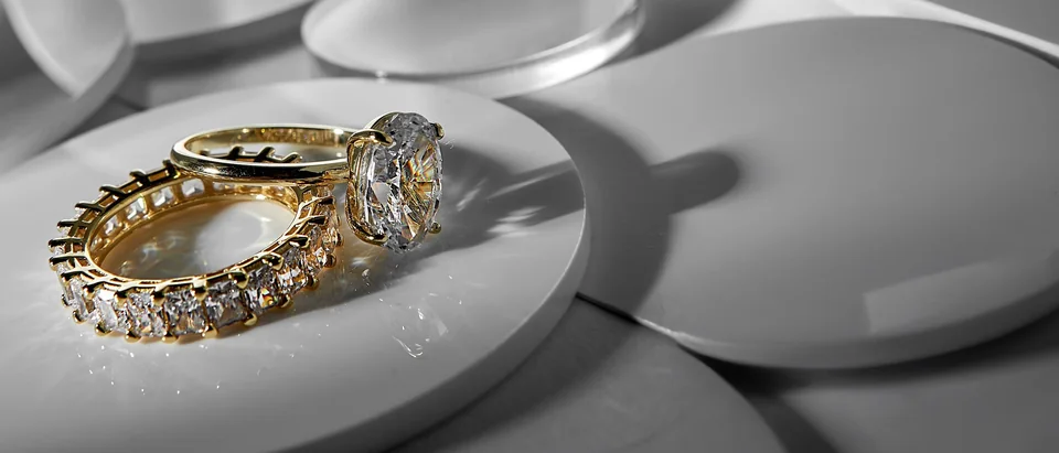 A gold eternity band and an oval diamond ring on a pale round dish