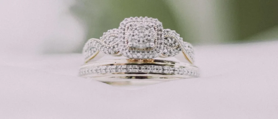 A cushion halo engagement ring stacked with a pave band on a white cushion