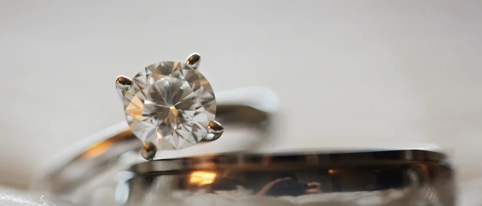 A round solitaire diamond ring in a four-prong setting resting on a band