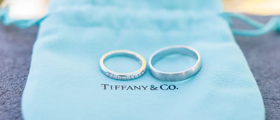 Two wedding bands resting on a blue Tiffany & Co. jewelry pouch