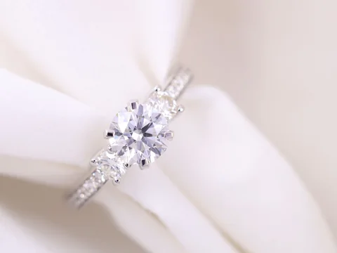 A three-stone diamond ring resting in folds of white silk