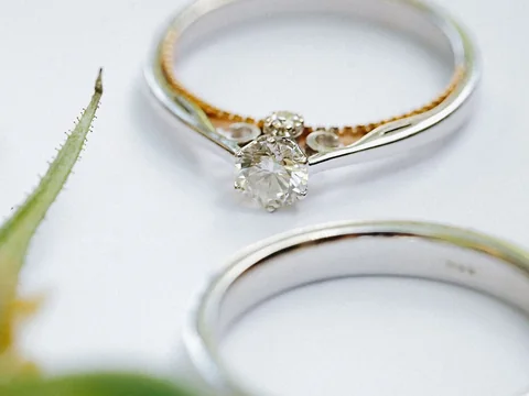 A solitaire diamond ring between two white gold bands on a white surface